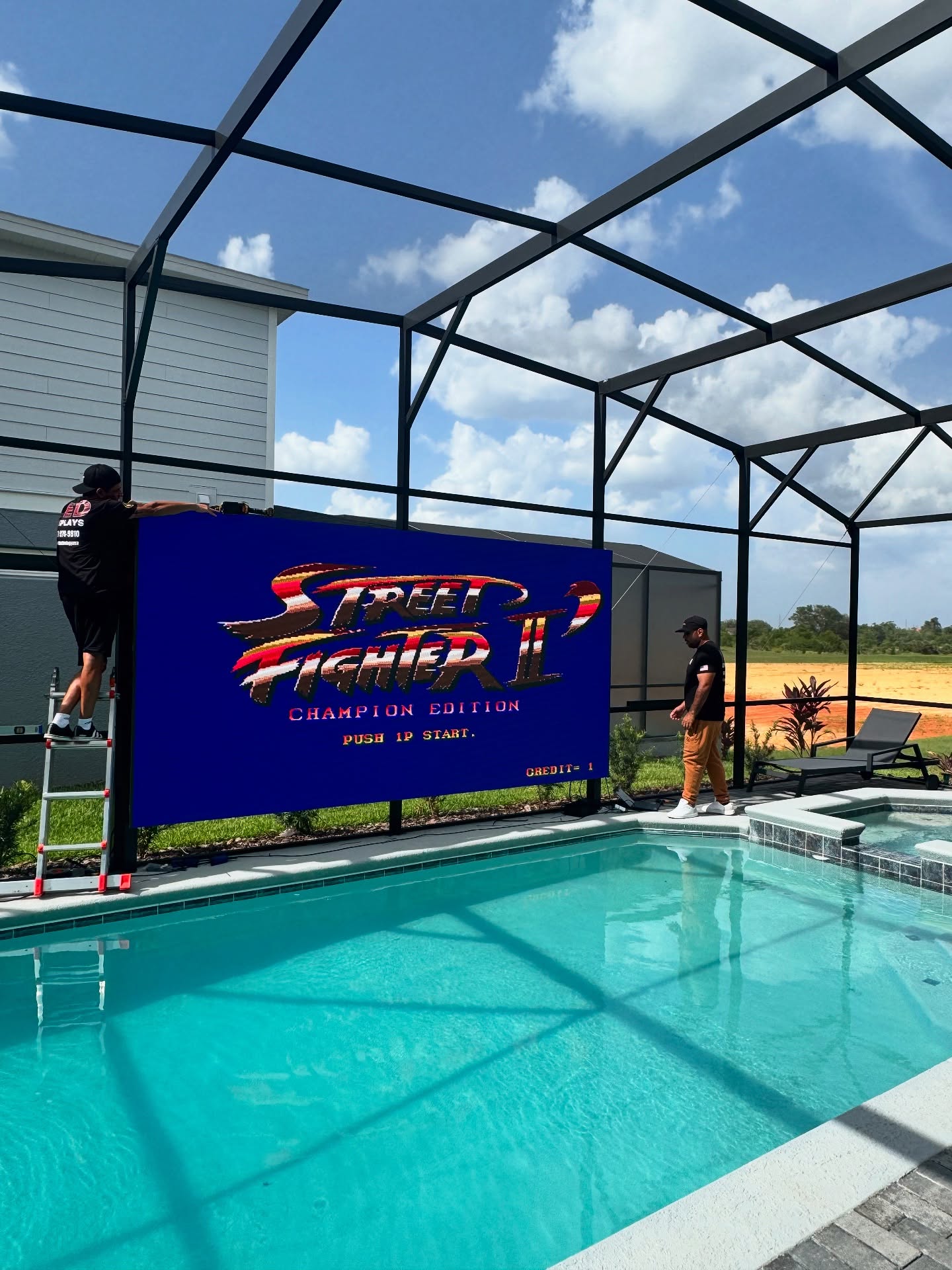 VB Technology outdoor LED display beside a swimming pool, shown as a third-party reference